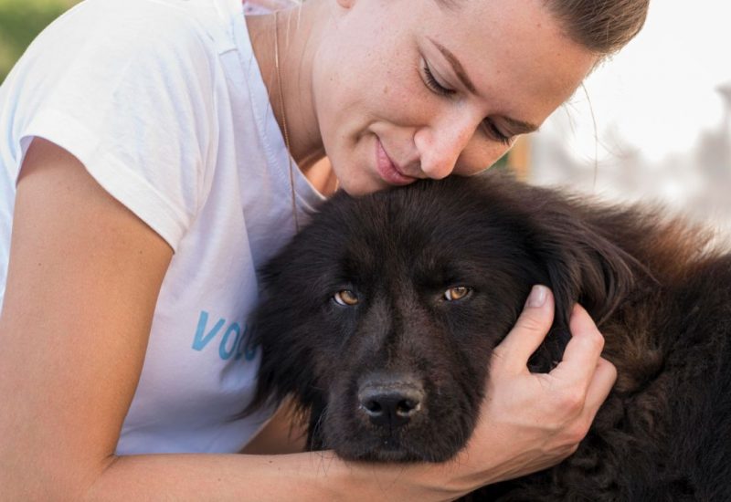 women hugging black dog